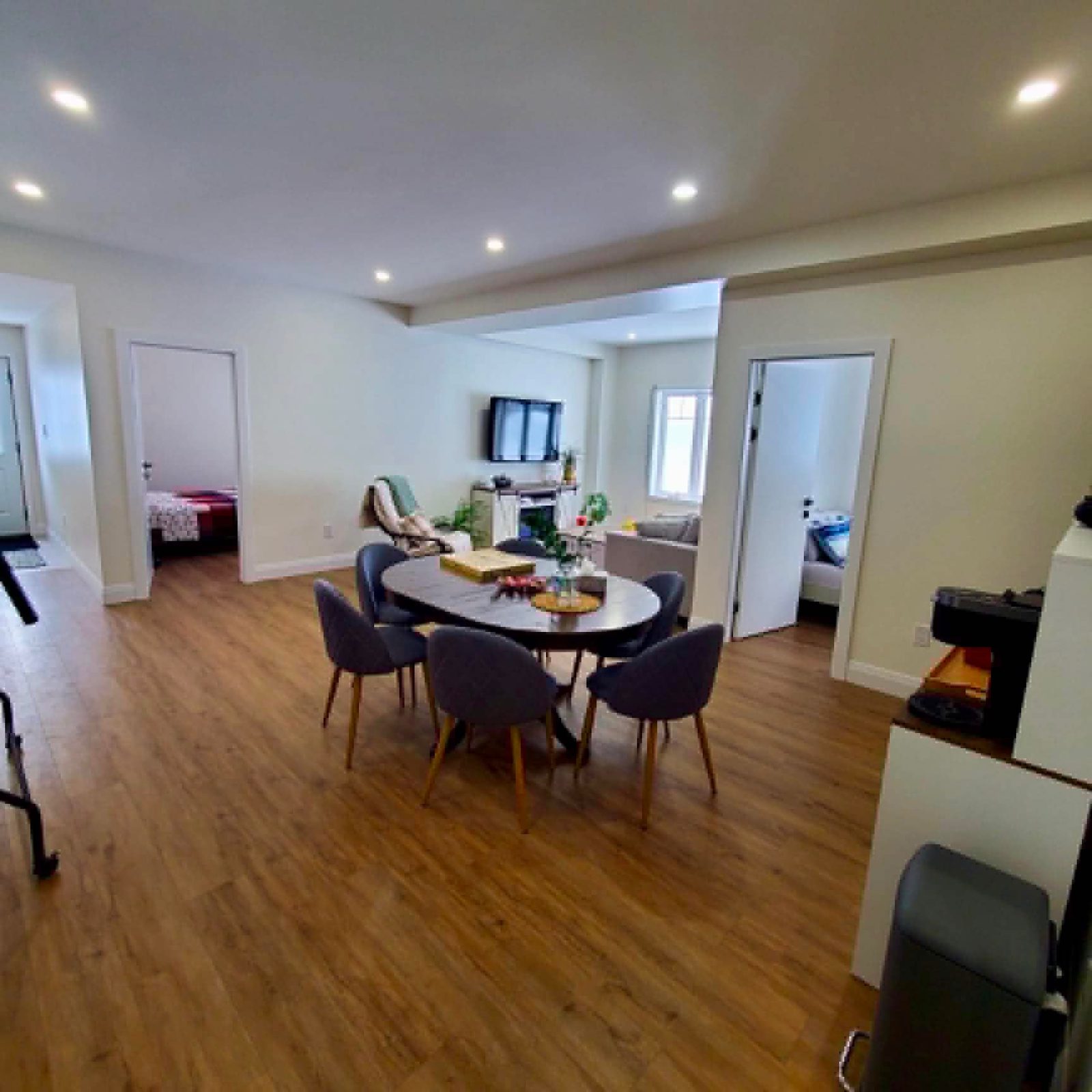 Basement open-concept suite with hallway to both bedrooms by ARK Renovation
